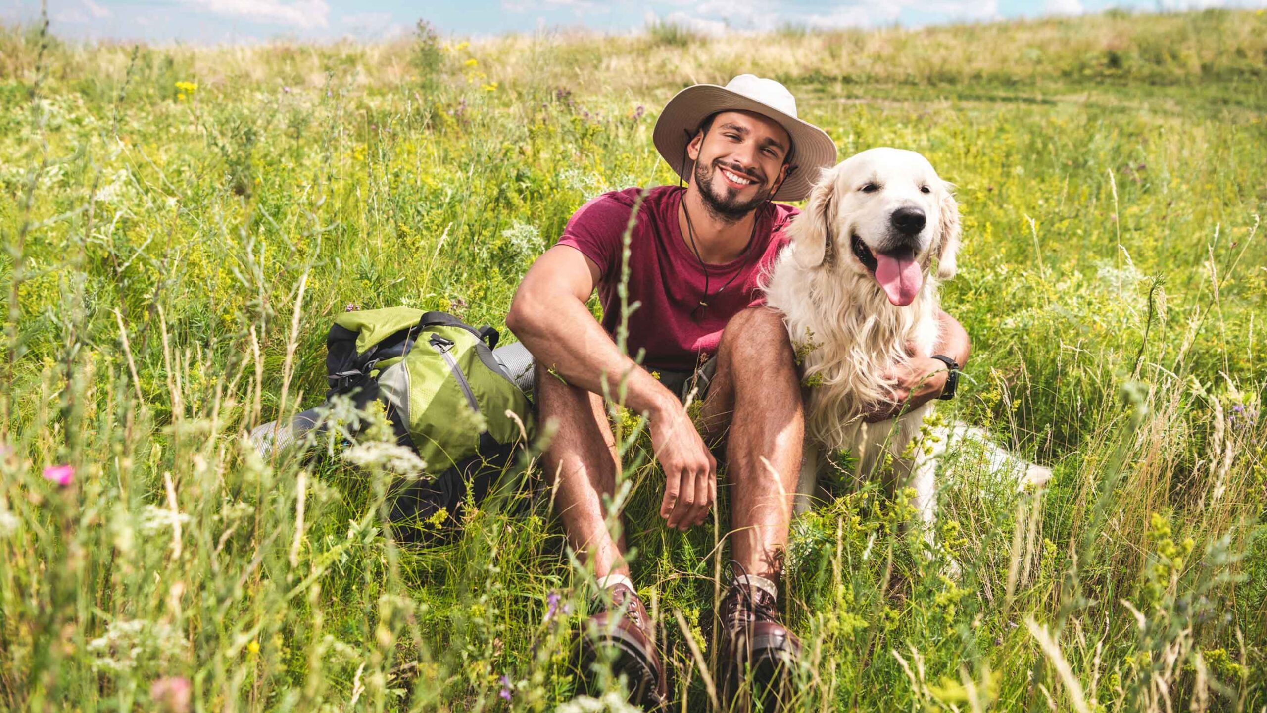 Mann mit seinem Hund in der Wiese sicher vor Zecken